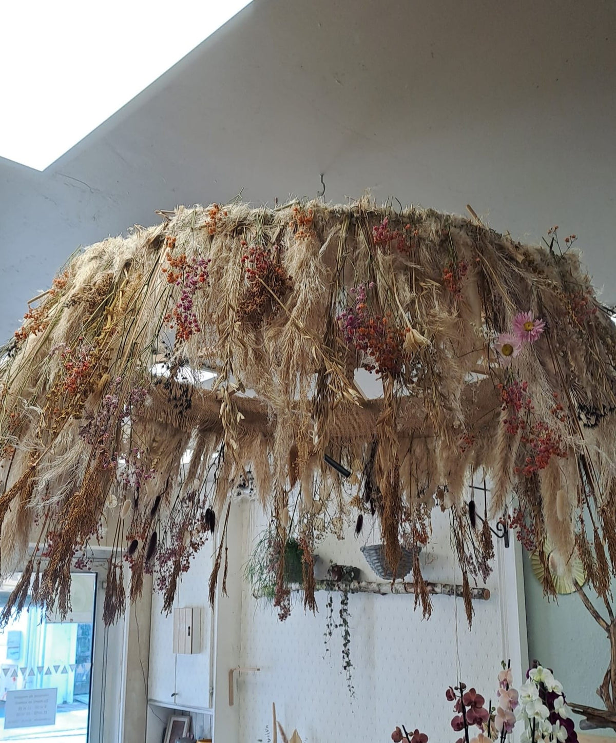 Suspension de fleurs et graminées séchées fabriquée à l'atelier d'Au Delà des Fleurs, idéale pour un restaurant ou un hall d'accueil