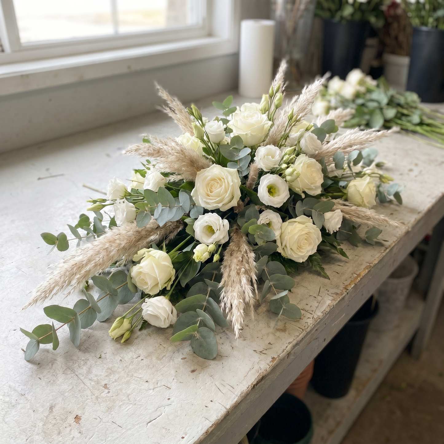 Raquette de deuil allongée, roses blanches et pampa avec eucalyptus